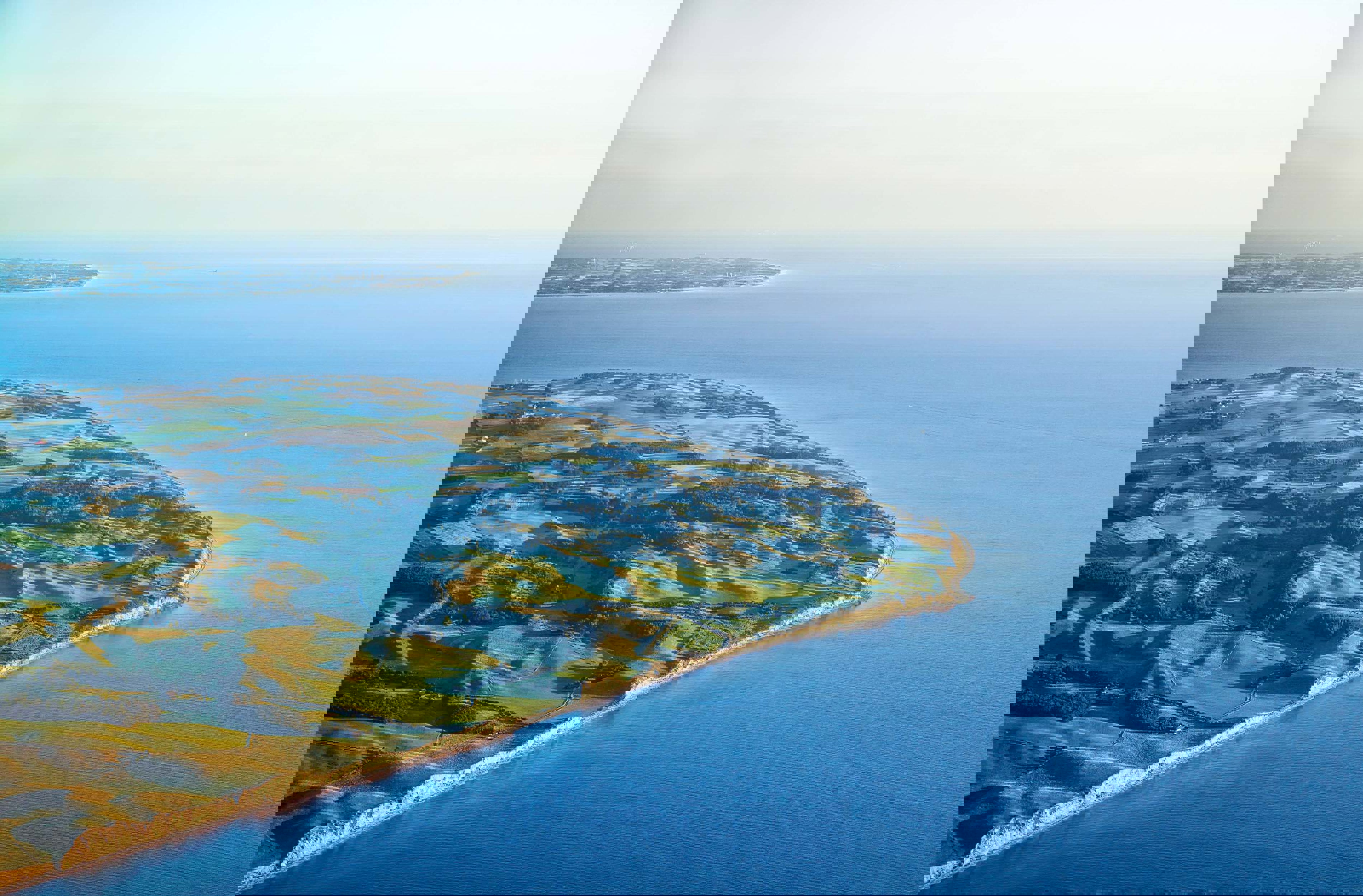 Aerial view of Samsoe island's coastline with clear blue waters and lush green landscape.