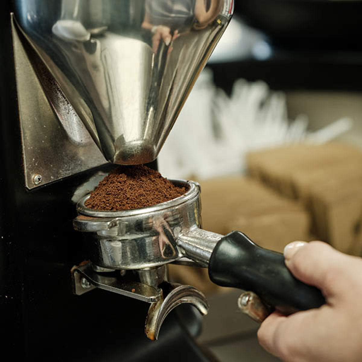 Coffee grinder processing fresh coffee beans into a portafilter holder, ready for brewing espresso.